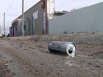 A beer can floats in a muddy ditch in Whiteclay Nebraska