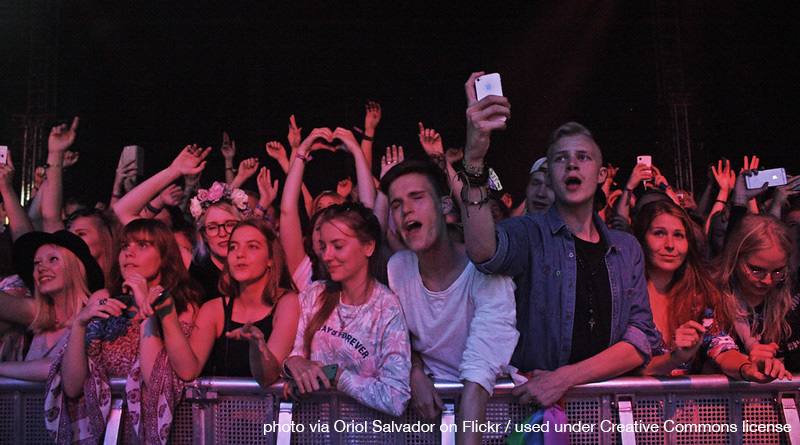 a group of youth crowd the rail at a concert, looking enthusiastic